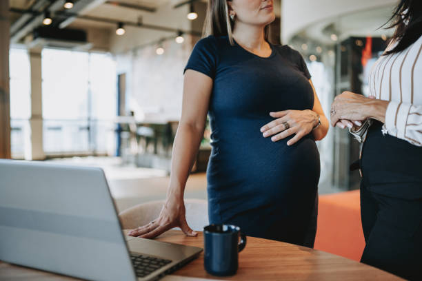 pregnant businesswoman talking to coworker.