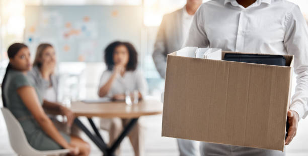 Employee carrying box of belongings from office after being terminated.