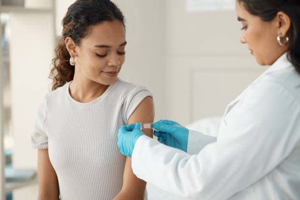 Woman receiving Band-Aid after vaccine from doctor.