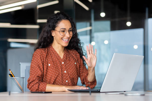 Working woman waving at computer scree.