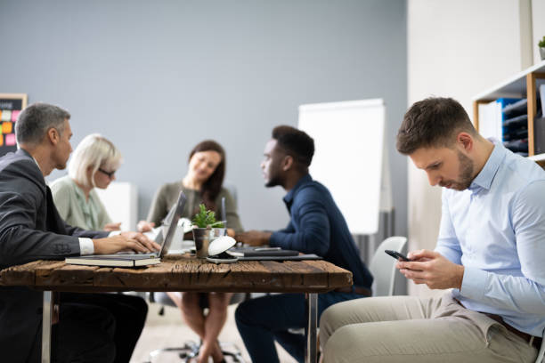 Distracted Businessman Using Mobile Phone In Meeting