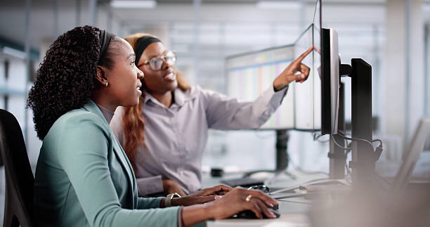 Efficient African American Accountant help younger worker on computer
