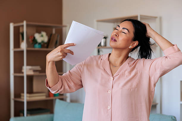 Woman experiencing hot flash fanning herself with a white paper